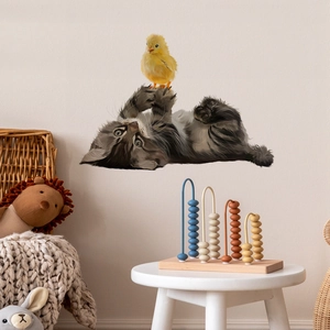 Détail d'un sticker mural chat tigré et poussin jaune dans un décor de chambre d'enfant doux