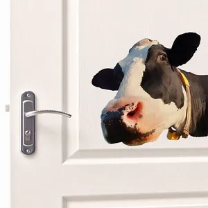 Close-up of a cute cow wall sticker with a yellow bell on a white interior door
