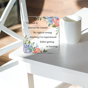 Detail of square acrylic ornament with floral motifs and inspirational quotes in sunlight