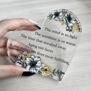 Macro shot of heart-shaped acrylic plaque featuring floral patterns and printed text