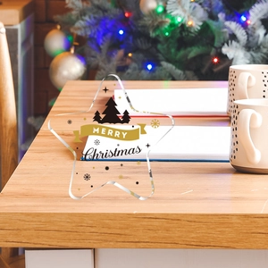 Close-up of a star-shaped acrylic Christmas ornament with gold silk-screen printing