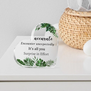 Macro shot of transparent acrylic heart decor with green leaf print and inspirational text