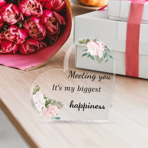 Detail of heart acrylic ornament with pink floral print and romantic quote on a gift box