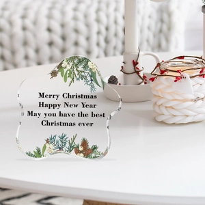 Macro shot of irregular acrylic Christmas ornament with holly leaves and New Year wishes