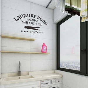 Detalle de vinilo decorativo negro Laundry Room con texto Wash Dry Fold en pared blanca