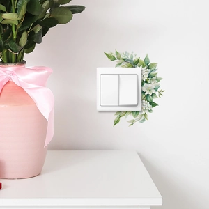 Watercolor green leaves and white flower wall stickers decorating a white light switch