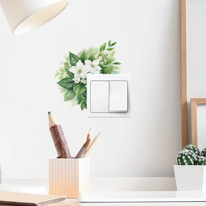 Detail of watercolor green leaves and white flower wall sticker around a white switch