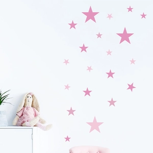 Stickers muraux étoiles roses de tailles variées sur mur blanc avec lapin décoratif et plante