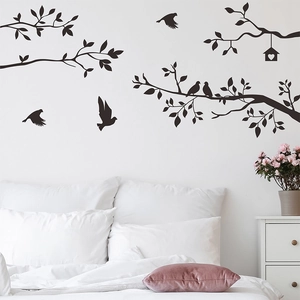 Detail view of black bird and tree branch wall decals on a minimalist white bedroom wall