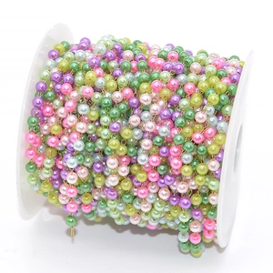 Close-up of colorful imitation pearl chain on white spool for DIY jewelry making