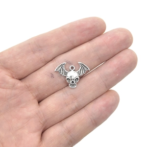Gothic winged skull charm in antique silver alloy held in hand for jewelry DIY projects
