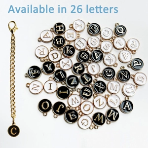 Detail view of 26 alphabet charms with gold metal frames and black and white enamel finishes