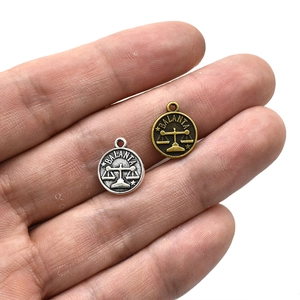 DIY Libra zodiac round pendant charms in silver and bronze metal finish shown on a palm