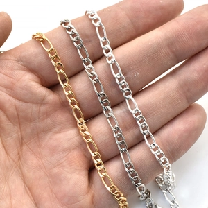 Trois colliers à chaîne Figaro en or et argent présentés sur main pour la taille