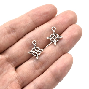 Amuletos Nudo de Bruja plateados para joyería DIY sostenidos en mano para ver el tamaño