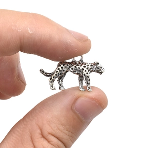 Macro-opname van een kleine zilveren luipaard hanger die de compacte maat laat zien