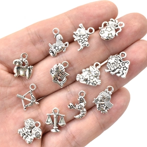 Set of 12 zodiac charms in antique silver alloy held in palm for DIY jewelry making
