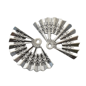 Detailed macro of two retro silver fan pendants with intricate hollow patterns