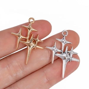 Shiny gold and silver star pendants for DIY jewelry making shown in hand for size