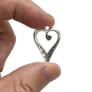 Vintage hollow heart pendant in antique silver with intricate embossed scroll patterns