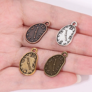 Vier metallische Vintage-Uhrenanhänger für DIY-Schmuck in der Hand zur Größenanzeige