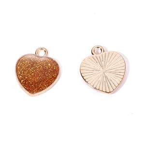 Macro shot of glitter heart pendants with gold frames and textured back detail