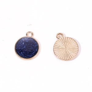 Detail of round golden alloy pendant featuring glittery dark blue starry sky finish
