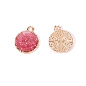 Macro shot of gold circular glitter pendants with pink resin and sunburst pattern