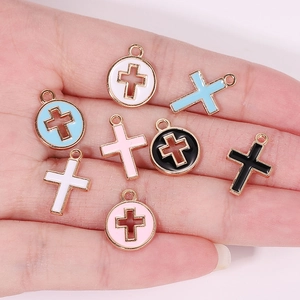 Macro shot of colorful enamel cross pendants in gold-plated alloy on a palm for scale