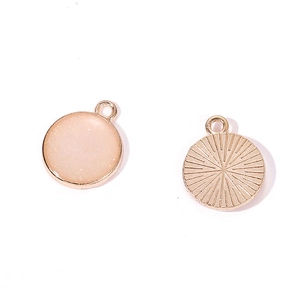 Detailed view of round alloy pendant with glitter resin and sunburst pattern engraving