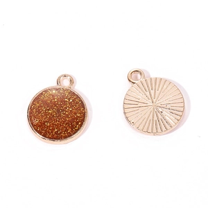 Macro detail of round alloy charm with gold texture backing and glitter resin front
