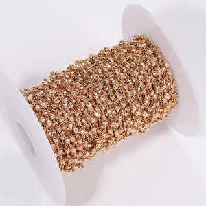 Macro detail of golden faceted bead chain on a spool for DIY jewelry and crafts