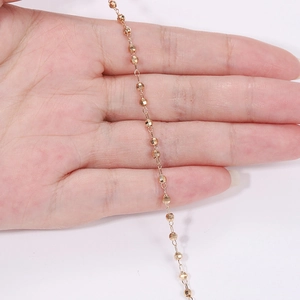 Macro detail of DIY rose gold laser faceted bead chain held by hand for jewelry crafting