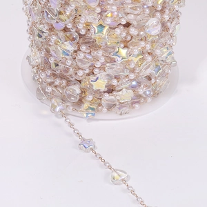 Macro view of DIY jewelry chain with pearls, iridescent stars and hearts on a roll