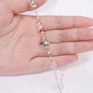 Detail of DIY jewelry chain with colorful star beads and pearls on a fine gold link