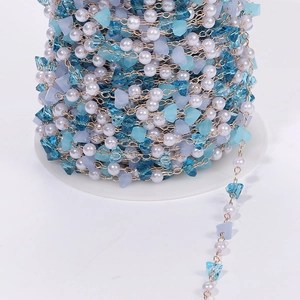 Detailed macro view of colorful crystal and pearl bead chain on a white plastic spool