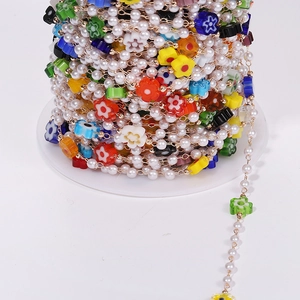 Detail von bunten Harzblumen und weißen Perlen auf einer Spule für DIY-Schmuckherstellung