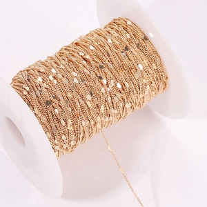 Detail of gold-plated copper heart link chain wrapped on a white plastic spool for DIY jewelry