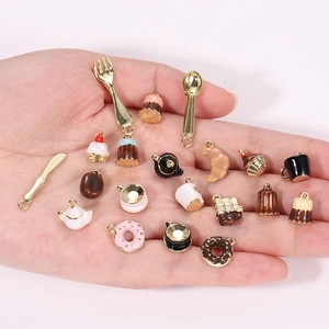 Hand holding 3D miniature food pendants like coffee cups and croissant charms