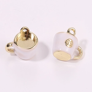 Macro detail of miniature 3D coffee cup charms with pink enamel and gold handles