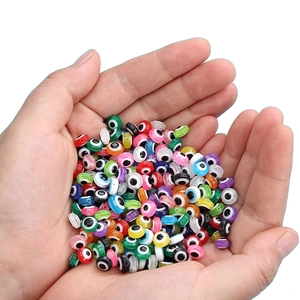 Close-up of colorful resin evil eye beads held in hands for DIY jewelry making