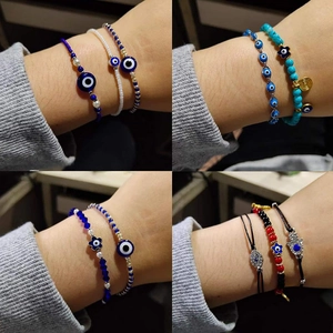 Detail of layered Hamsa Hand and Evil Eye beaded bracelets on a female wrist
