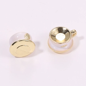 Detailed close-up of miniature gold-plated white enamel coffee cup and saucer charms