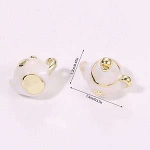 Macro shot of 3D miniature teapot pendants with pearl white finish and gold trim details