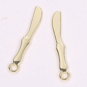 Detailed macro view of golden miniature spreader charms with hanging loops for DIY jewelry