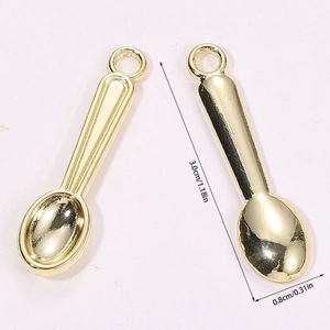 Macro view of miniature golden spoon charms with precise dimensions and ring loops