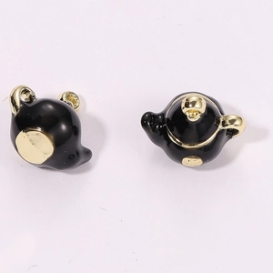 Macro view of 3D miniature black teapot charms with gold plated details for DIY jewelry