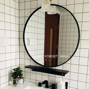 Moderner runder Wandspiegel mit schwarzem Rahmen und Regal auf weißem Fliesenbadhintergrund