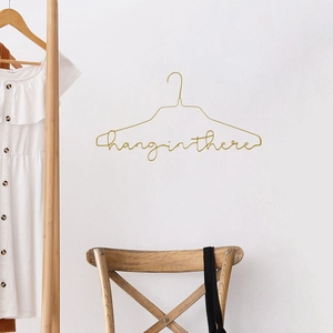 Minimalist gold metal wire hanger featuring creative 'hang in there' cursive typography