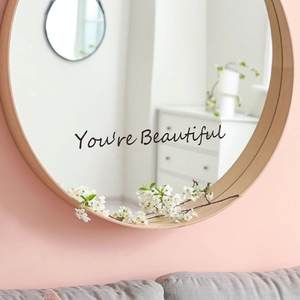 Round wooden wall mirror with You're Beautiful lettering in a cozy living room decor